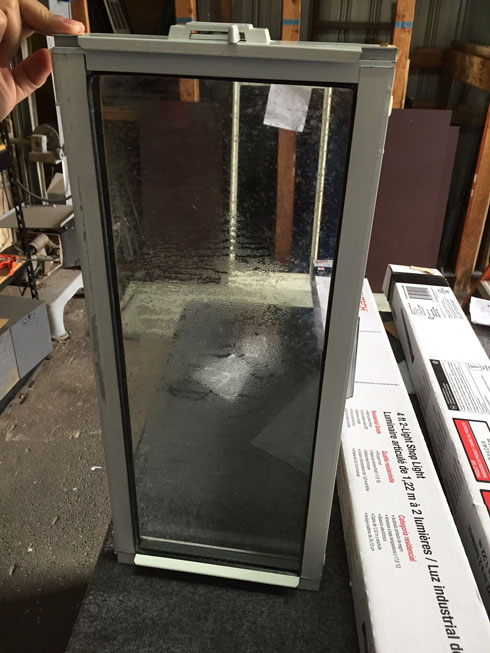 A dual pane window with water droplets between the glass panes due to a bad seal.