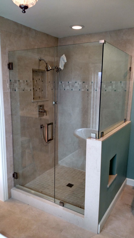 A frameless shower enclosure with a return panel in a brushed nickel finish.