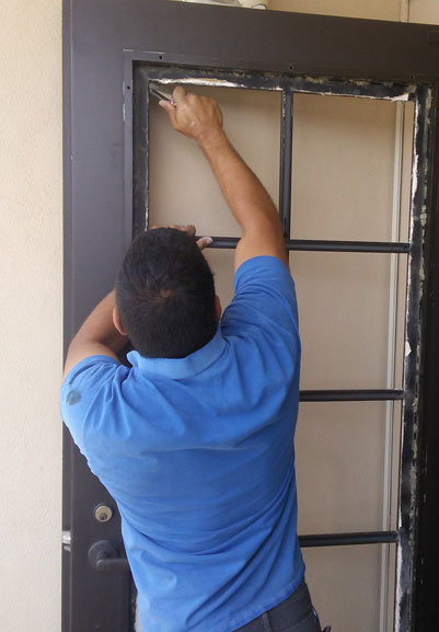 A National Glass technician installs a piece of replacement dual pane glass in a french door.