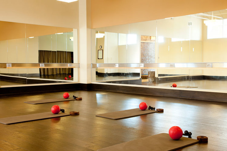 A yoga studio with wall to wall mirrors.